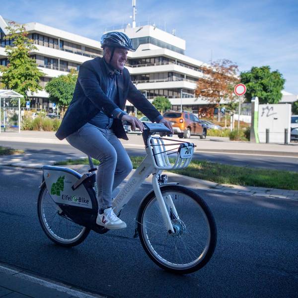 Landrat Markus Ramers radelt mit seinem E-Bike an der Kreisverwaltung in Euskirchen vorbei.