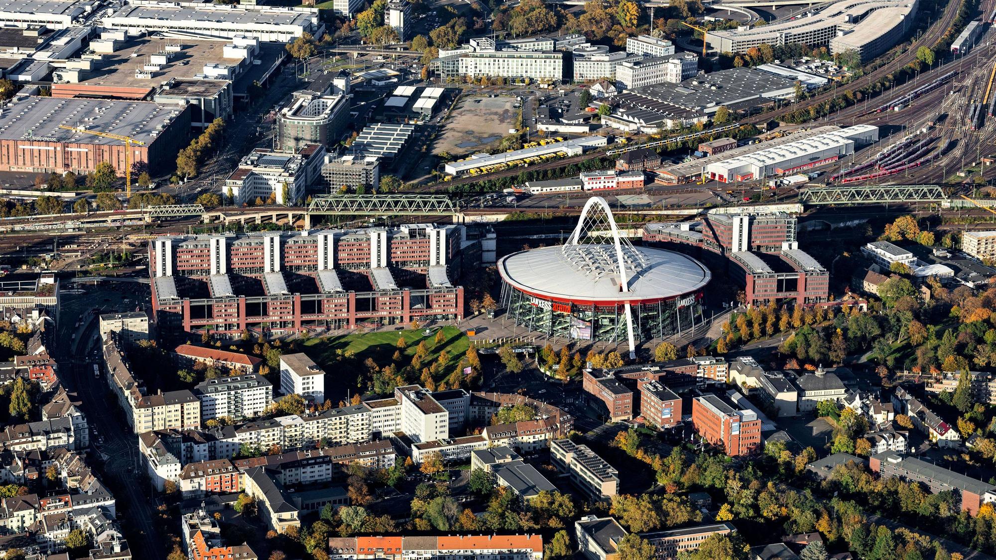 Blick von oben auf die Lanxess-Arena in der Mitte und links und rechts davon das Technische Rathaus mit seinem West- und Ost-Teil.