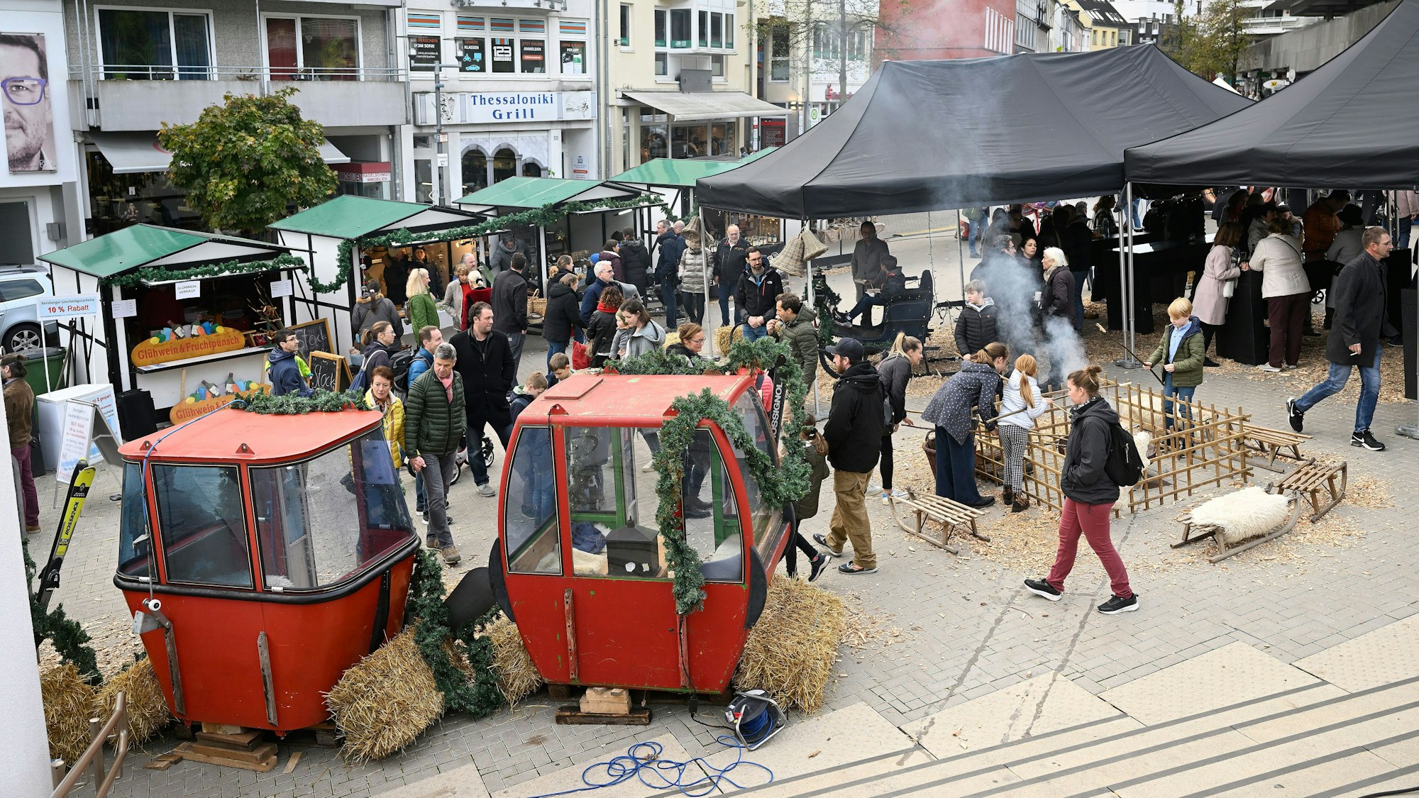 Zu sehen sind zwei rote Gondeln, davor laufen Besucher des Festes entlang.