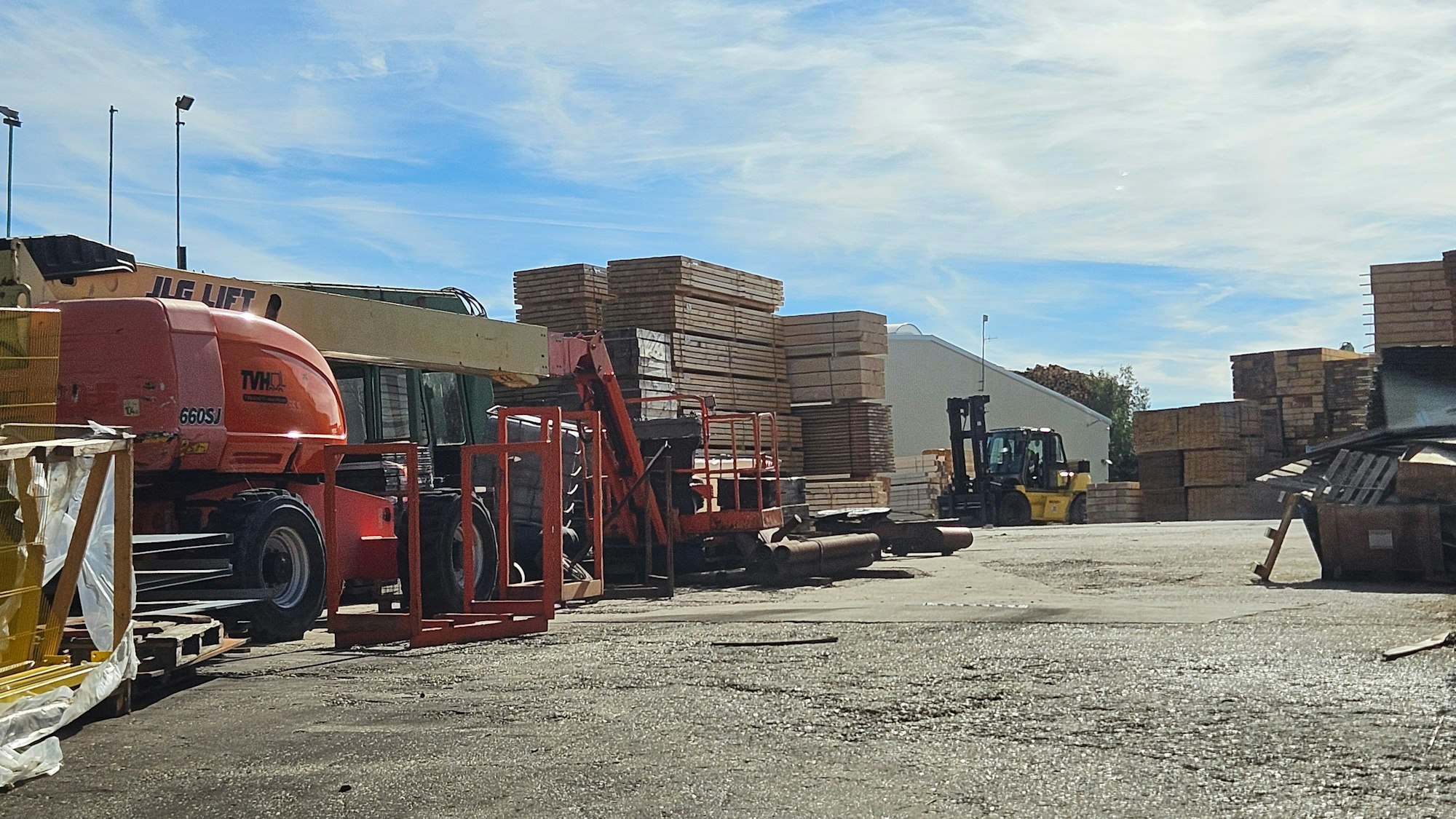 Blick auf den Hof des Sägewerks in Harperscheid,wo Maschinen und Paletten mit Brettern stehen.