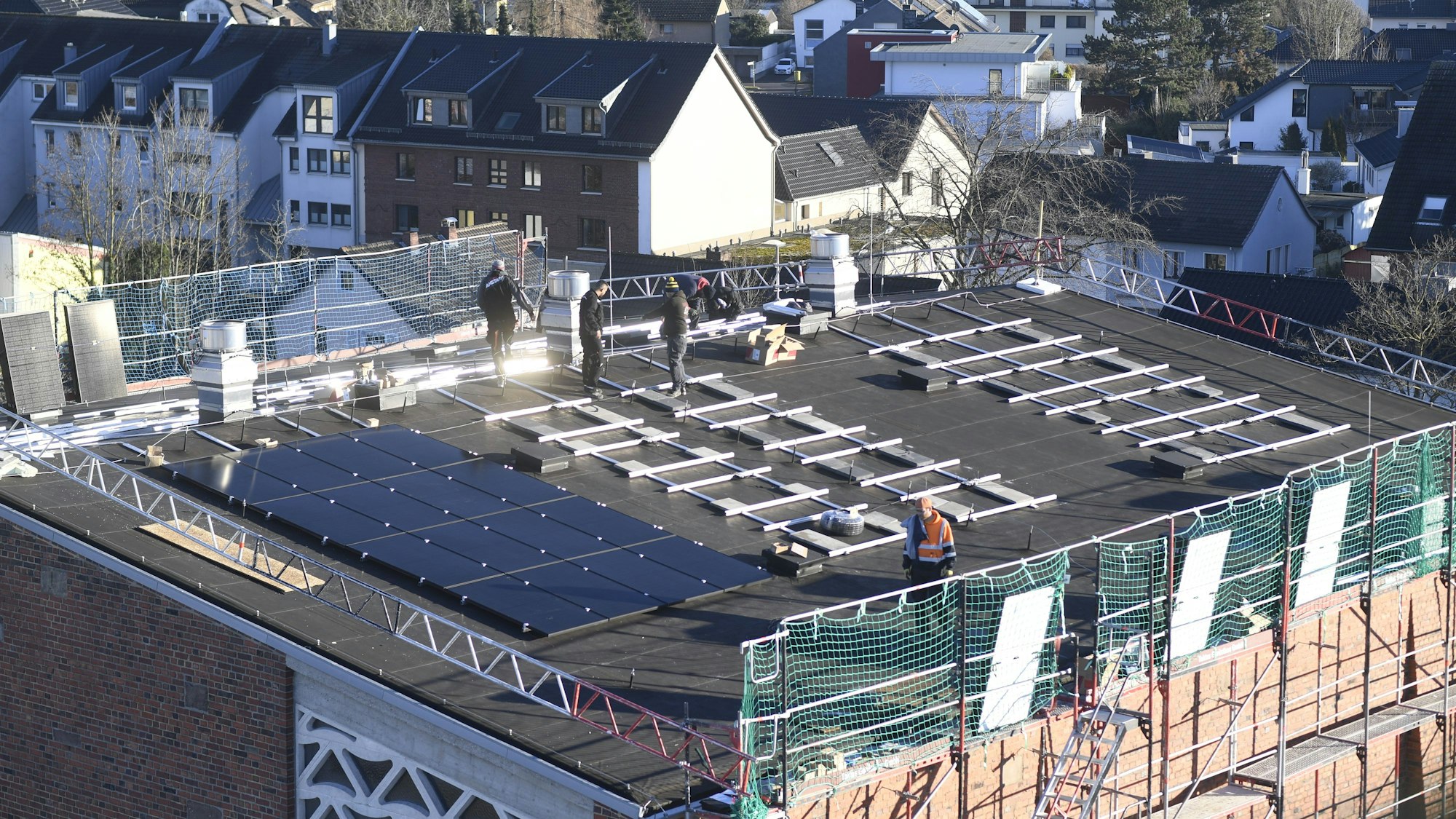 Bauarbeiter installieren Solarmodule auf dem Dach einer Kirche.