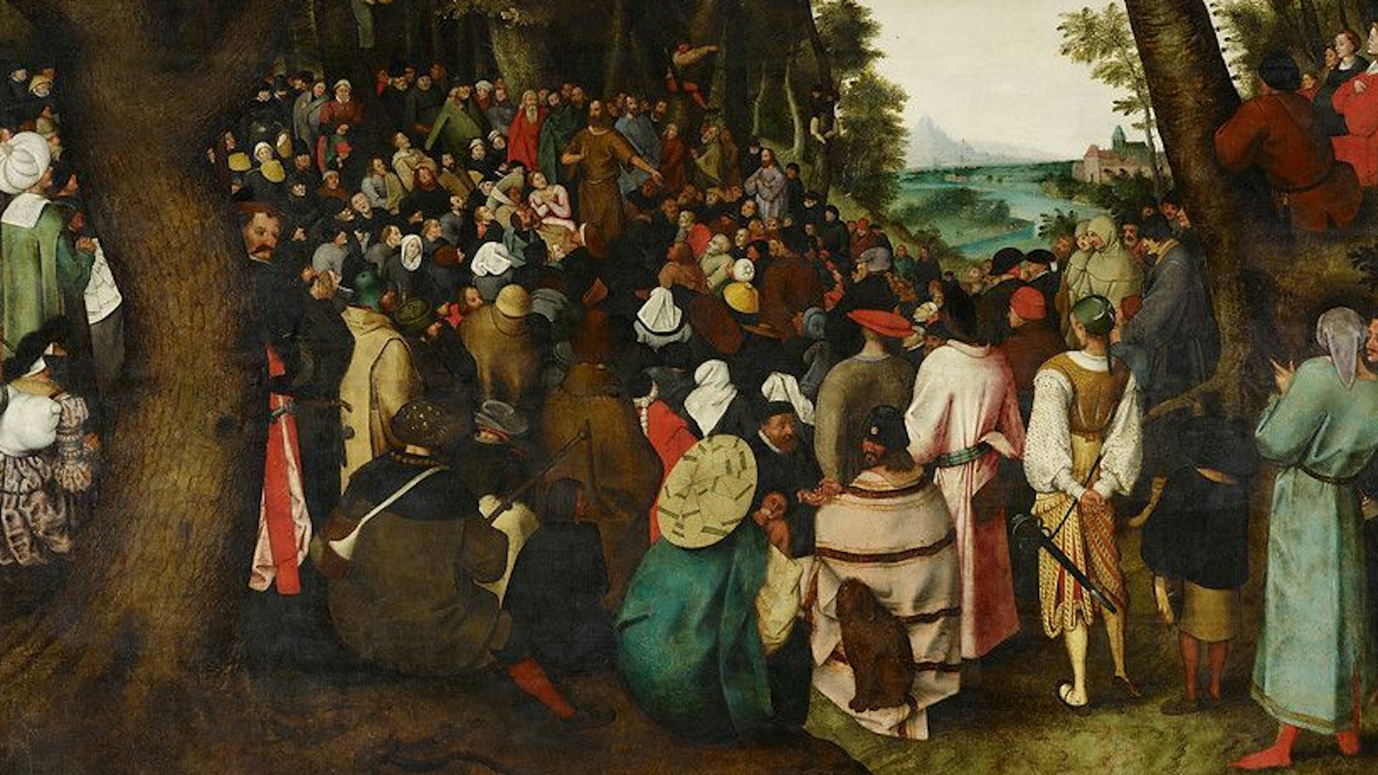 Viele Menschen lauschen einem Prediger im Wald.