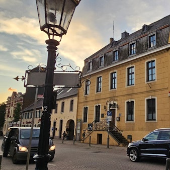 An einem prächtigen gelben alten Haus fahren Autos vorbei.