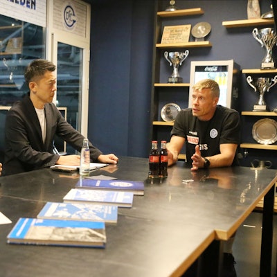 Am Tisch sitzen VfL-Trainer Gudjon-Valur Sigurdsson mit Ayumu Muta und Akyama Shigeki.