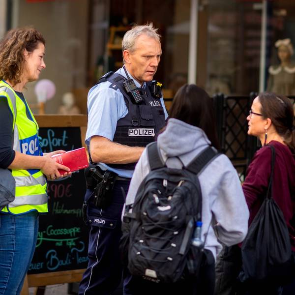 Das Bild zeigt Markus Braun in Polizeiuniform und Simone Becker in gelber Warnweste im Gespräch mit zwei Frauen.