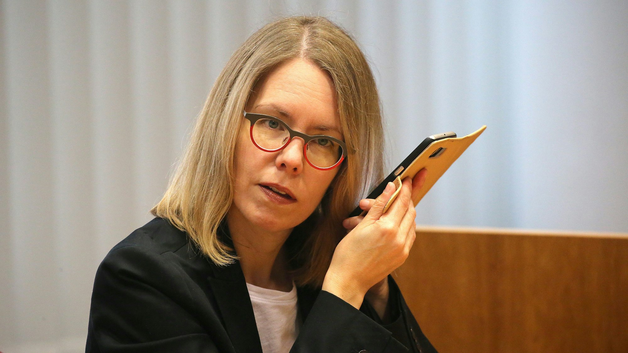 ARCHIV - 18.03.2020, Nordrhein-Westfalen, Bonn: Anne Brorhilker, Oberstaatsanwältin, hört am Rande eines Prozesses um Cum-Ex-Deals im Landgericht in ihr Smartphone. (zu dpa «Cum-Ex-Ermittlungen: Hauptabteilung wird aufgeteilt - Vorwürfe») Foto: Oliver Berg/dpa +++ dpa-Bildfunk +++