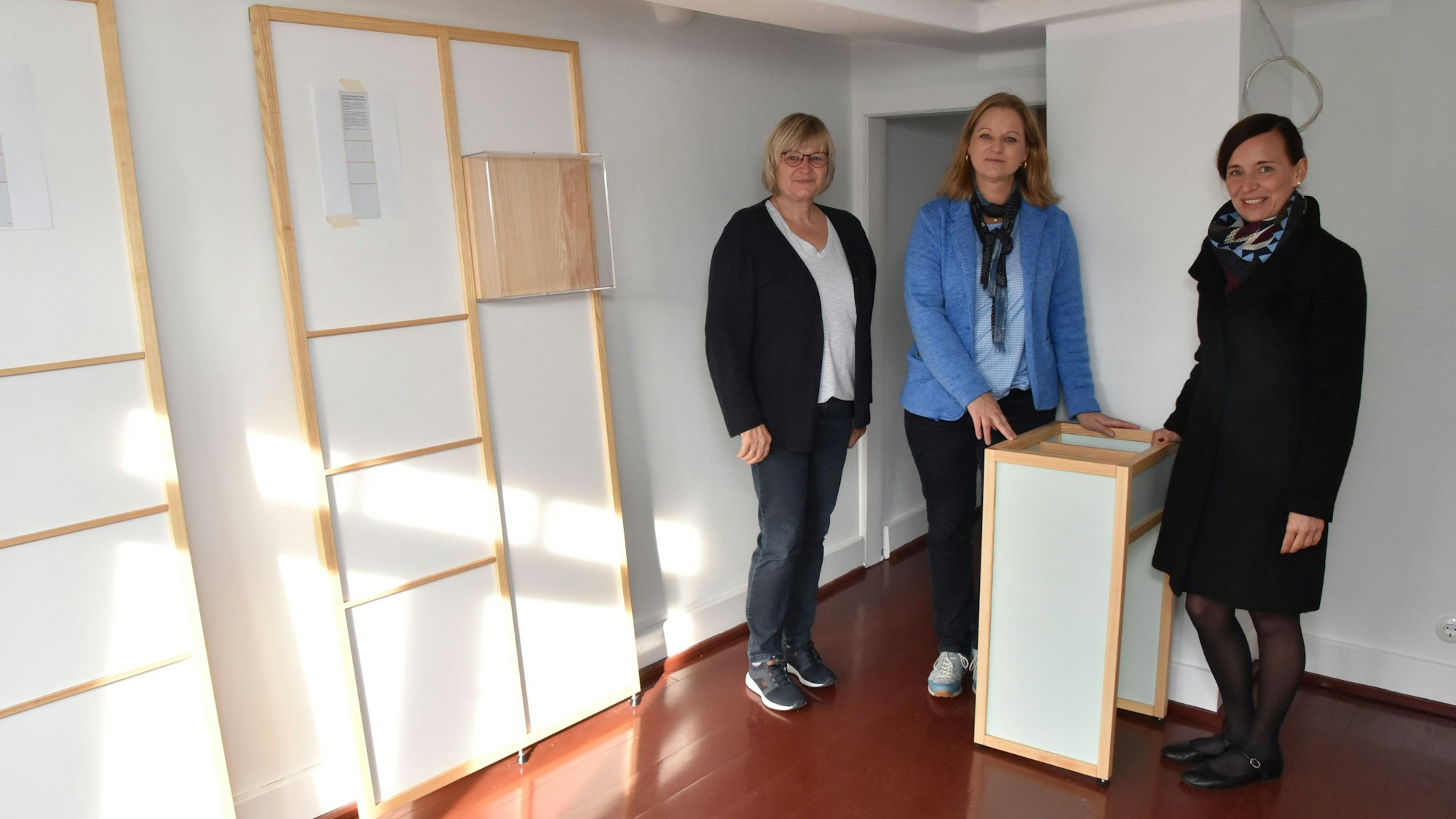 Drei Damen stehen in einem Zimmer mit neuen Ausstellungsmöbeln.