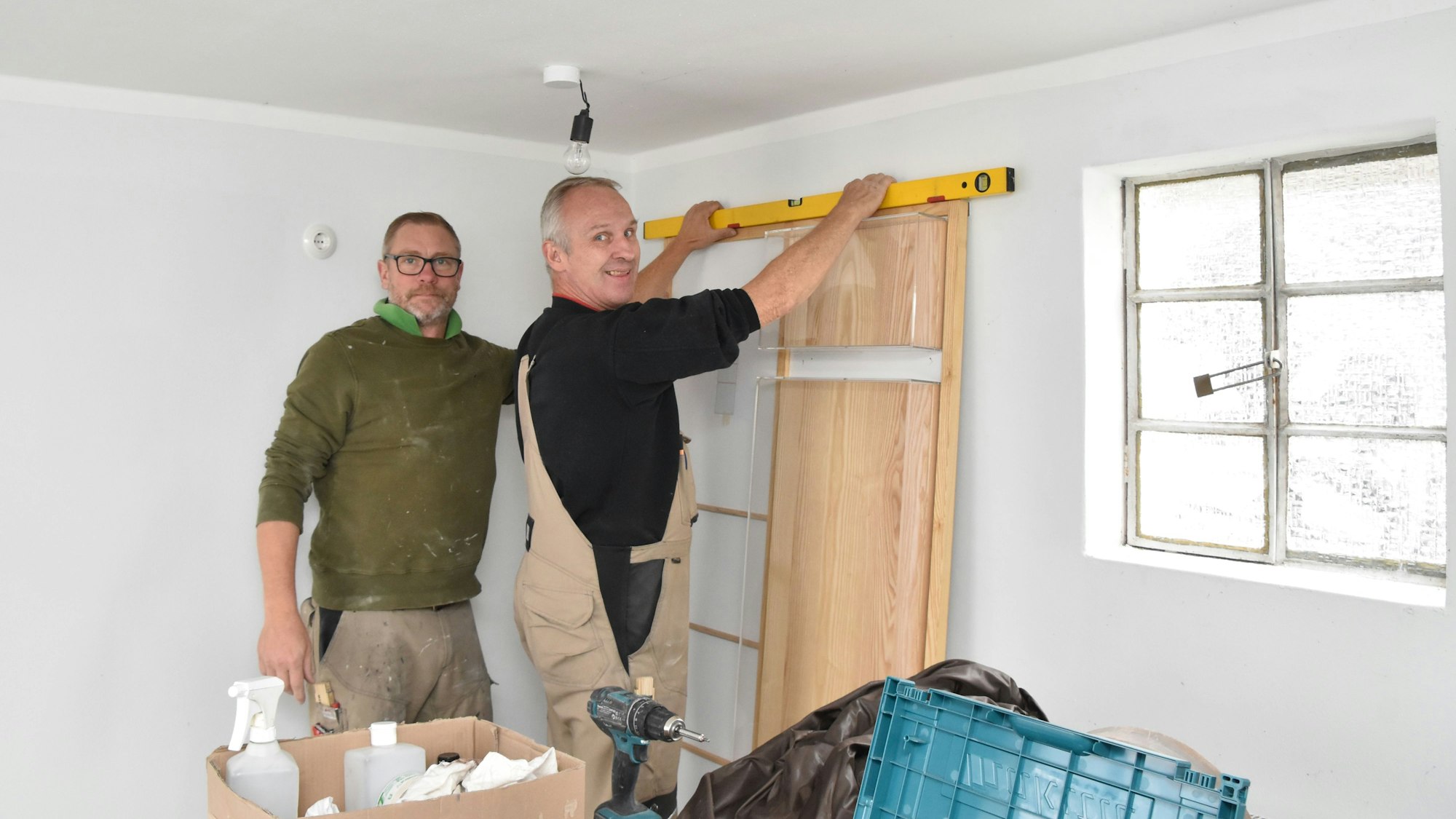 Zwei Handwerker montieren die neuen Ausstellungsmöbel in einem Raum der Gedenkstätte.