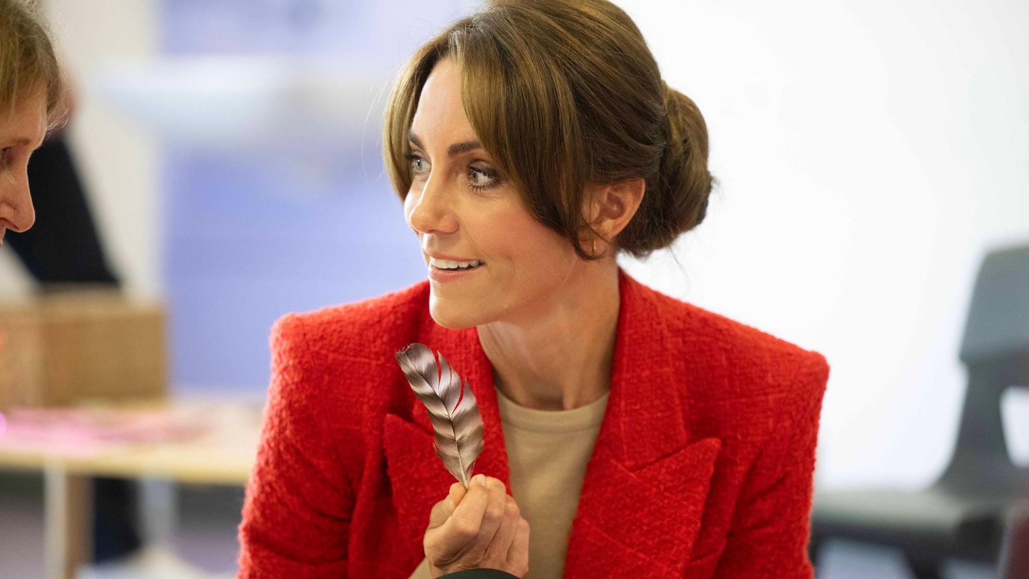 Die Prinzessin von Wales hält eine Feder in der Hand und blickt zur Seite.