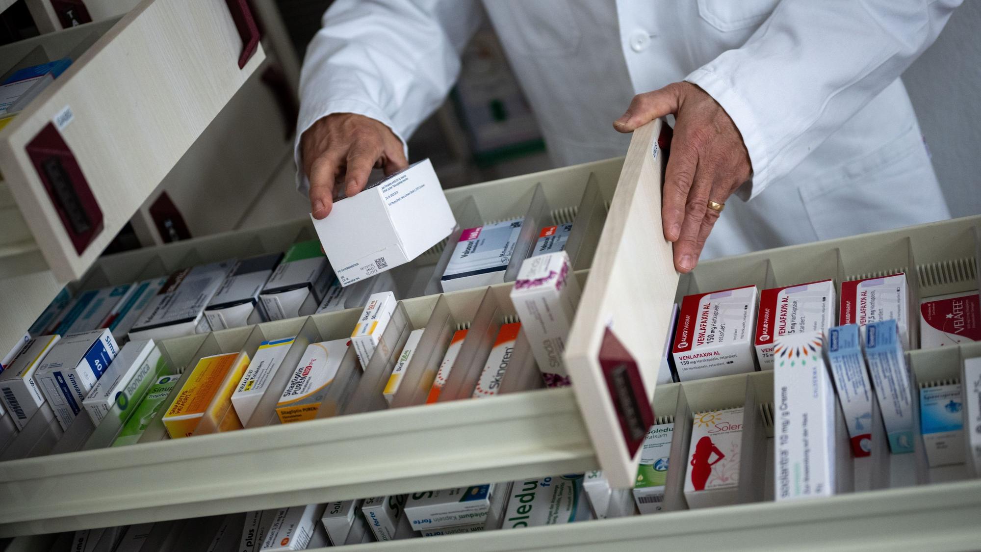 ILLUSTRATION - 05.06.2023, Berlin: Ein Apotheker holt eine Medikamentenverpackung aus einer Schublade in einer Apotheke. Bestimmte Medikamente können bei Hitze gefährliche Nebenwirkungen verursachen. Das geht aus einem am Mittwoch veröffentlichten Bericht des Robert Koch-Instituts (RKI) hervor. (zu dpa «Hitze kann gefährliche Nebenwirkungen bei Medikamenten auslösen») Foto: Monika Skolimowska/dpa +++ dpa-Bildfunk +++