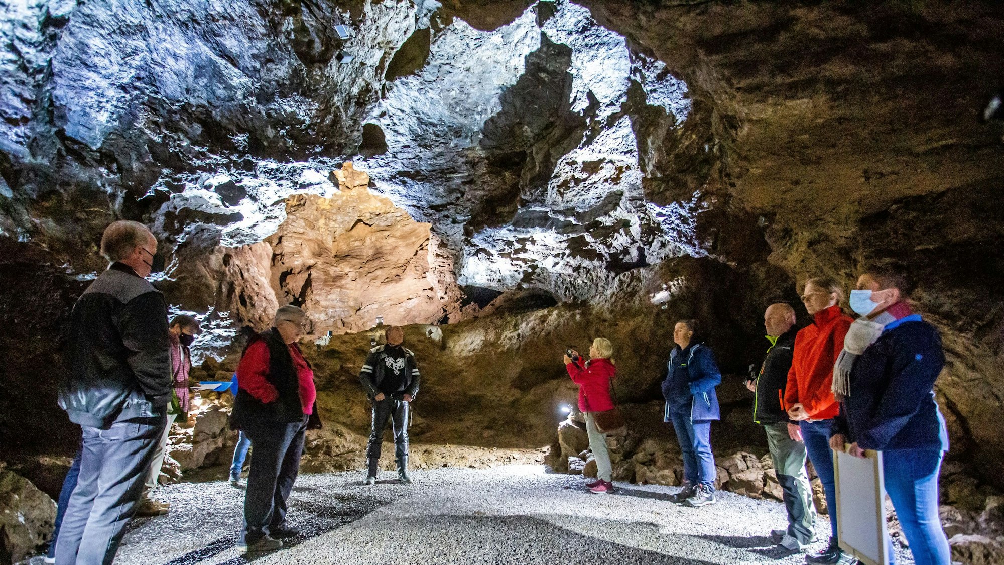 Eine Gruppe von Menschen steht mit Anoraks und Schals bekleidet in der Aggertalhöhle.