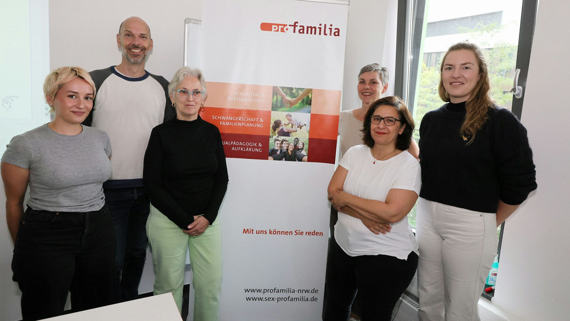 Mehrere Personen stehen vor einem Banner von Pro Familia.