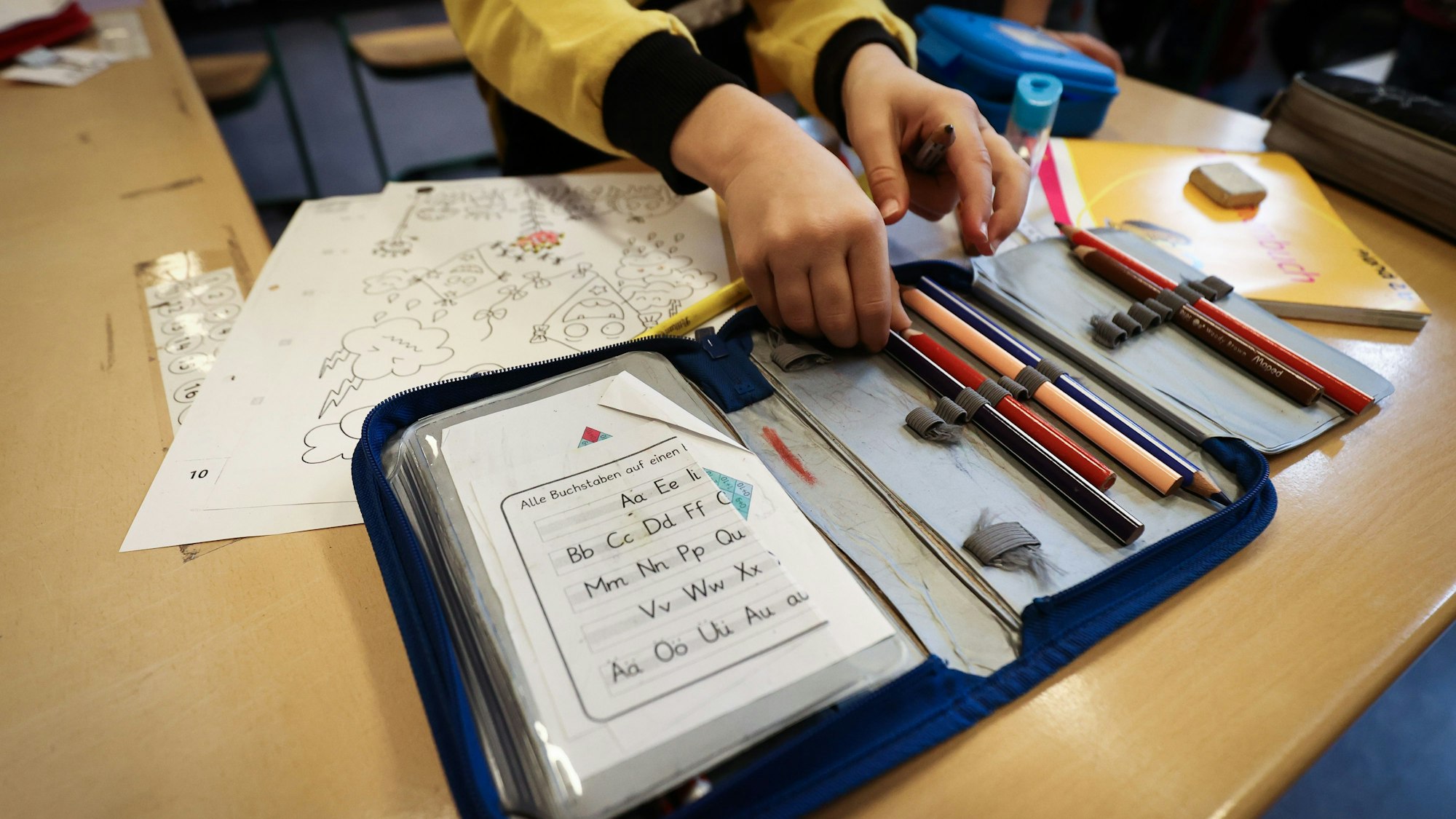 Ein Schüler greift nach einem Stift aus seiner Stiftemappe mit einem Zettel mit den Buchstaben des Alphabets in einer 2. Klasse in der Grundschule Hasselbrook. Die Bundeskanzlerin berät in einer Video-Konferenz mit den Ministerpräsidenten über weitere Corona-Beschränkungen. Schulen und Kitas sollen aber offen bleiben. +++ dpa-Bildfunk +++