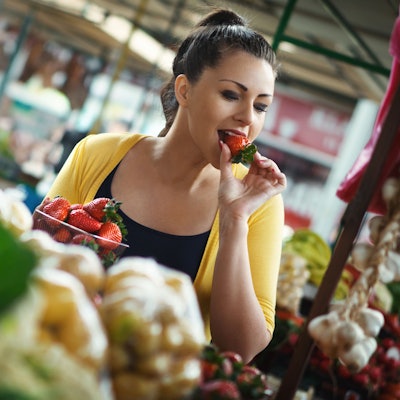 Frau probiert eine Erdbeere im Supermarkt.