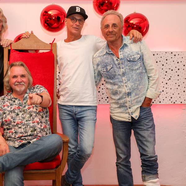 Jürgen Fritz, Tommy Engel, Peter Brings und Erry Stoklosa posieren im Rahmen des Pressegesprächs für ein Foto. Engel sitzt dabei auf einem Stuhl.