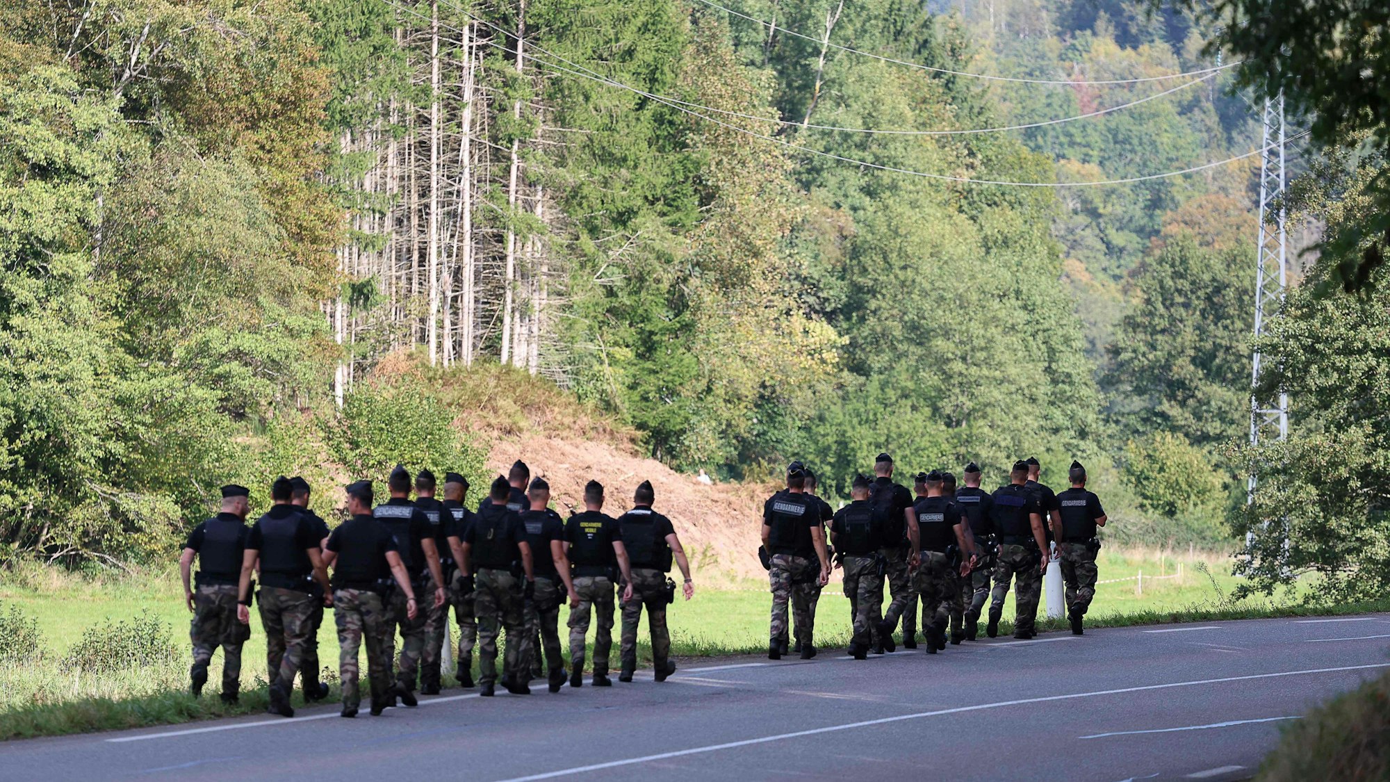 Französische Gendarmen laufen auf der Suche nach der verschwundenen Lina durch ein Waldstück.