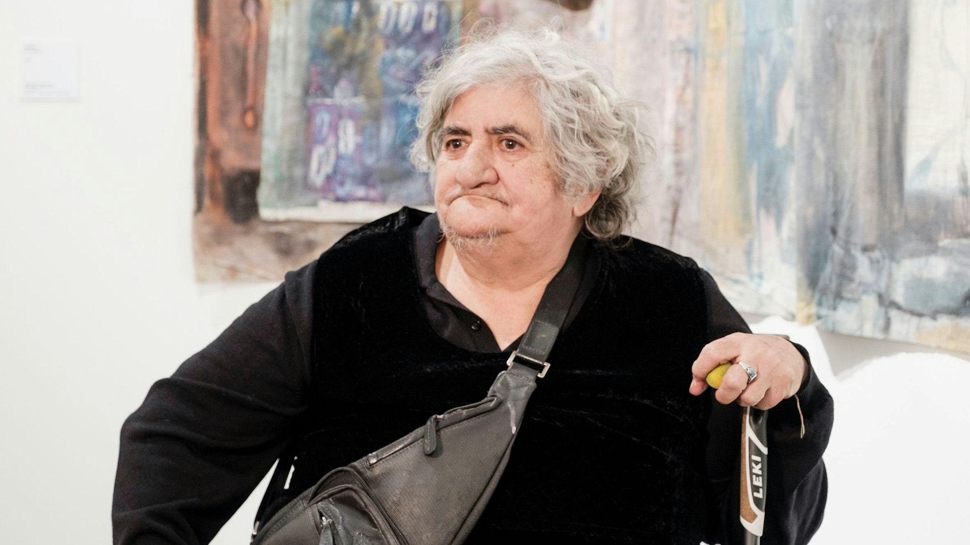 Anna Boghiguian sitzt mit einem Stock vor einem ihrer Were.