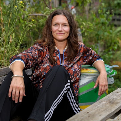 21.09.2023, Köln: Die Regisseurin Marie Bues sitzt auf einer Holzbank im Carlsgarten des Schauspiels Köln.