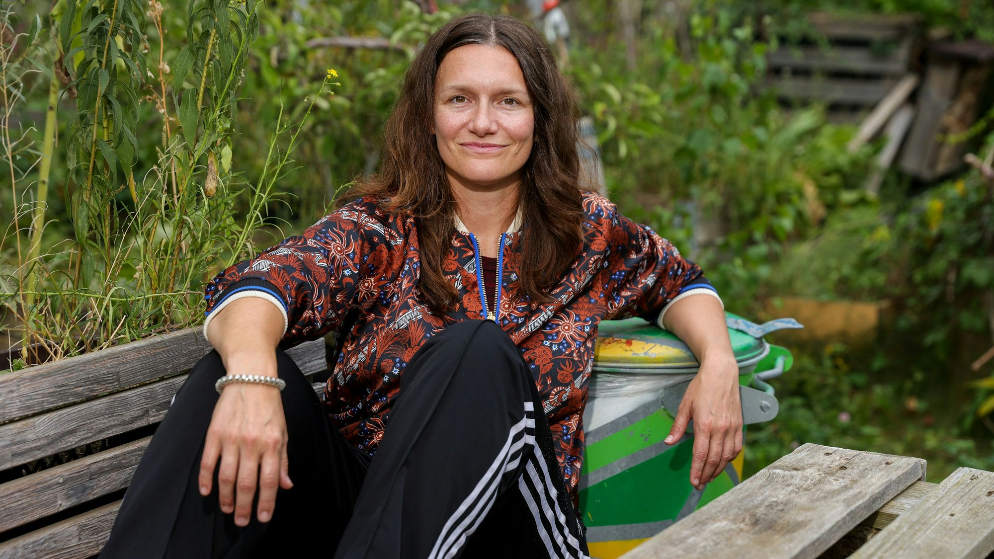 21.09.2023, Köln: Die Regisseurin Marie Bues sitzt auf einer Holzbank im Carlsgarten des Schauspiels Köln.