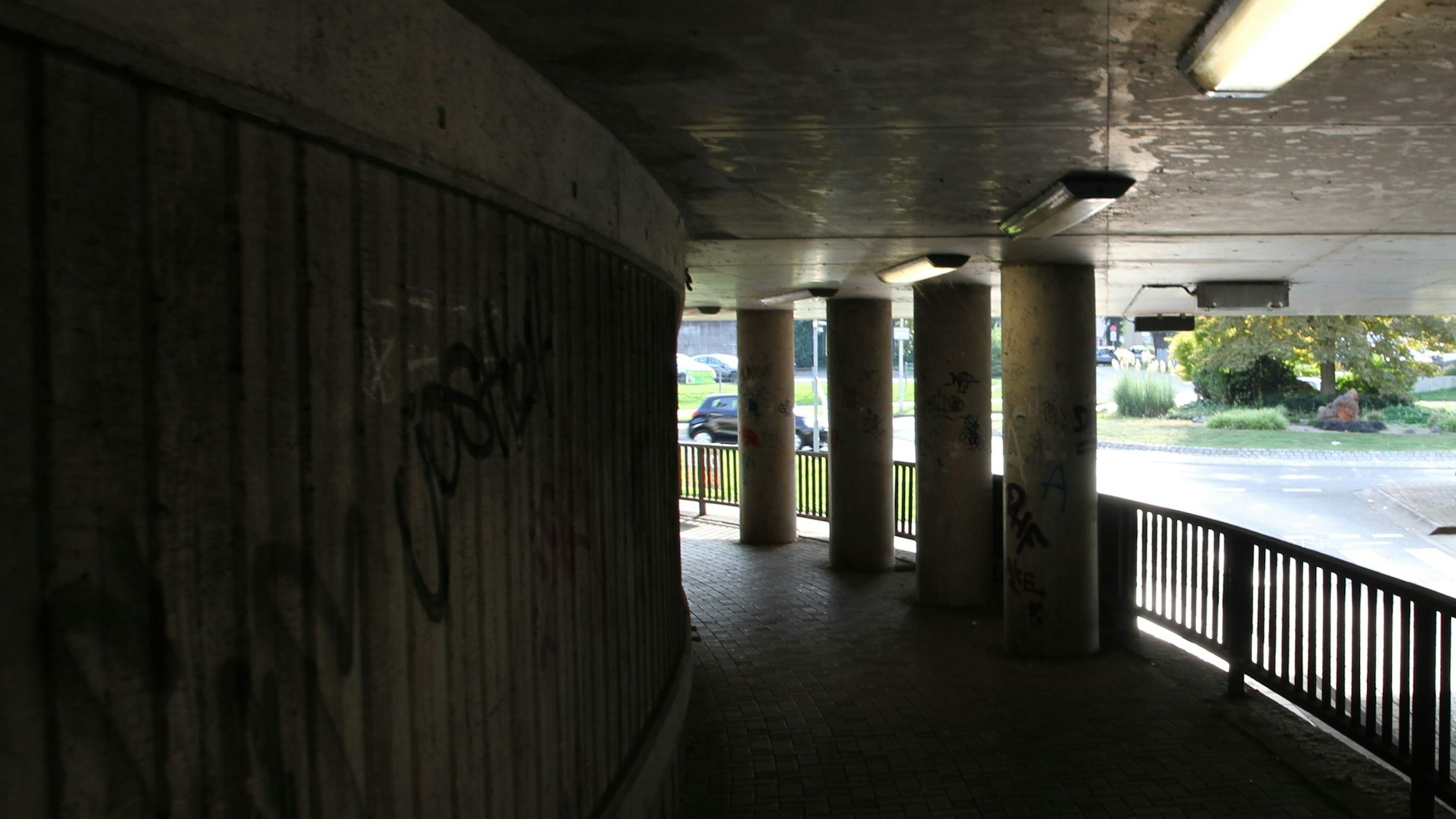 Blick aus einer dunklen Bahnunterführung auf einen Kreisverkehr