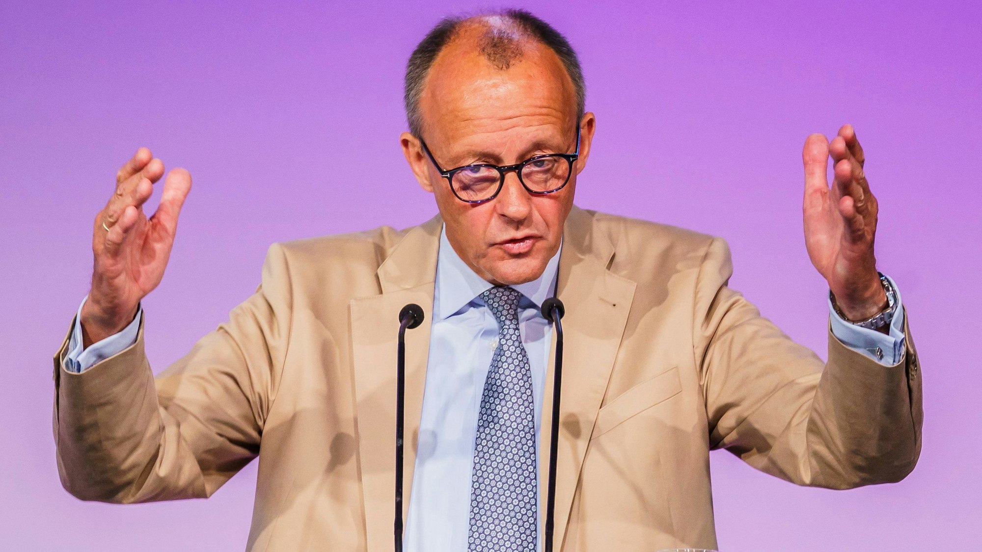 Der CDU-Vorsitzende Friedrich Merz hebt bei einer Rede beide Arme nach oben und gestikuliert vor einem Rednerpult.
