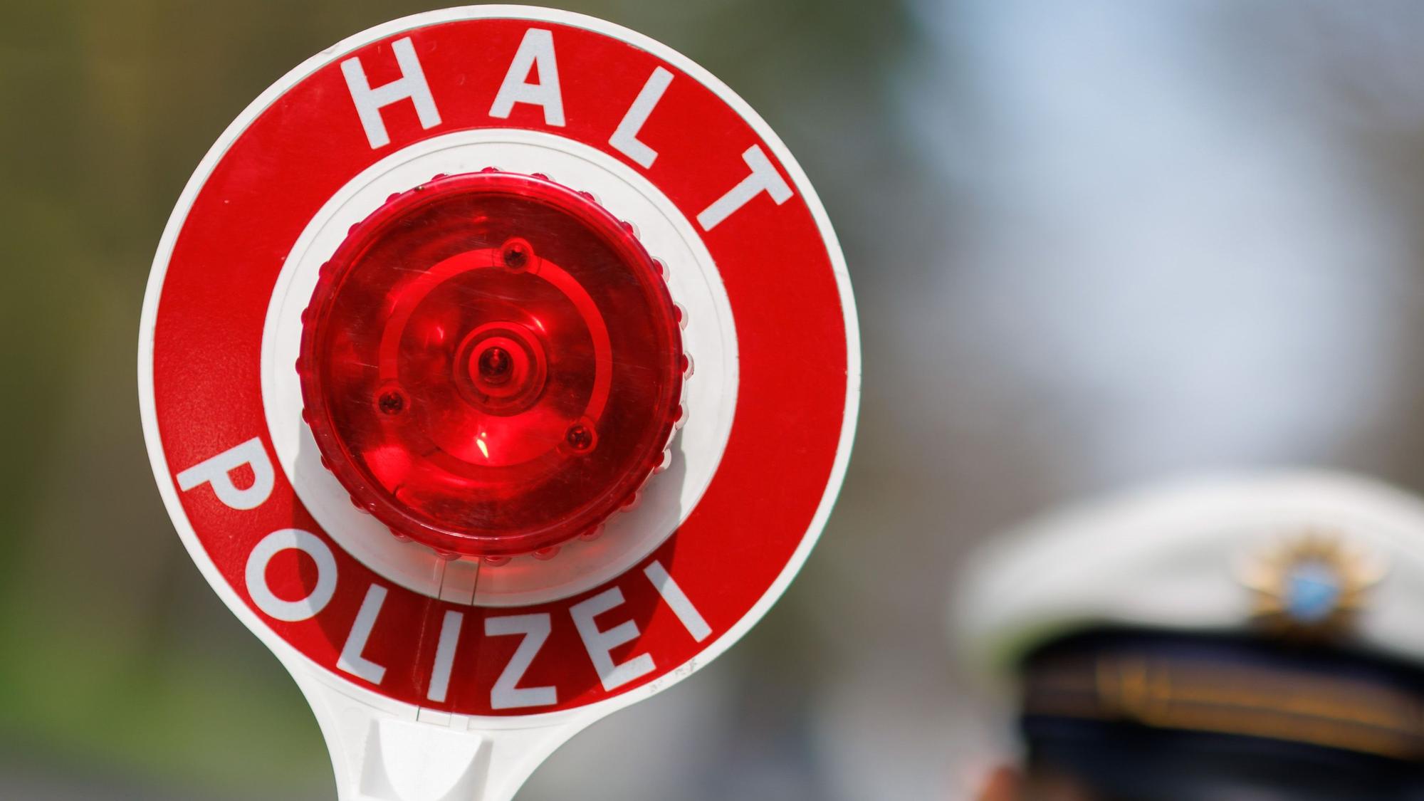 Ein Polizist zieht ein Fahrzeug mit seiner Kelle aus dem Verkehr.
