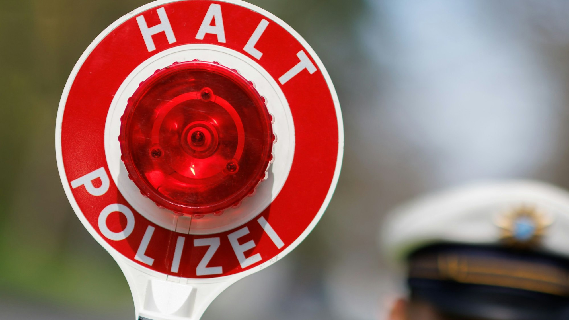 Ein Polizist zieht ein Fahrzeug mit seiner Kelle aus dem Verkehr.