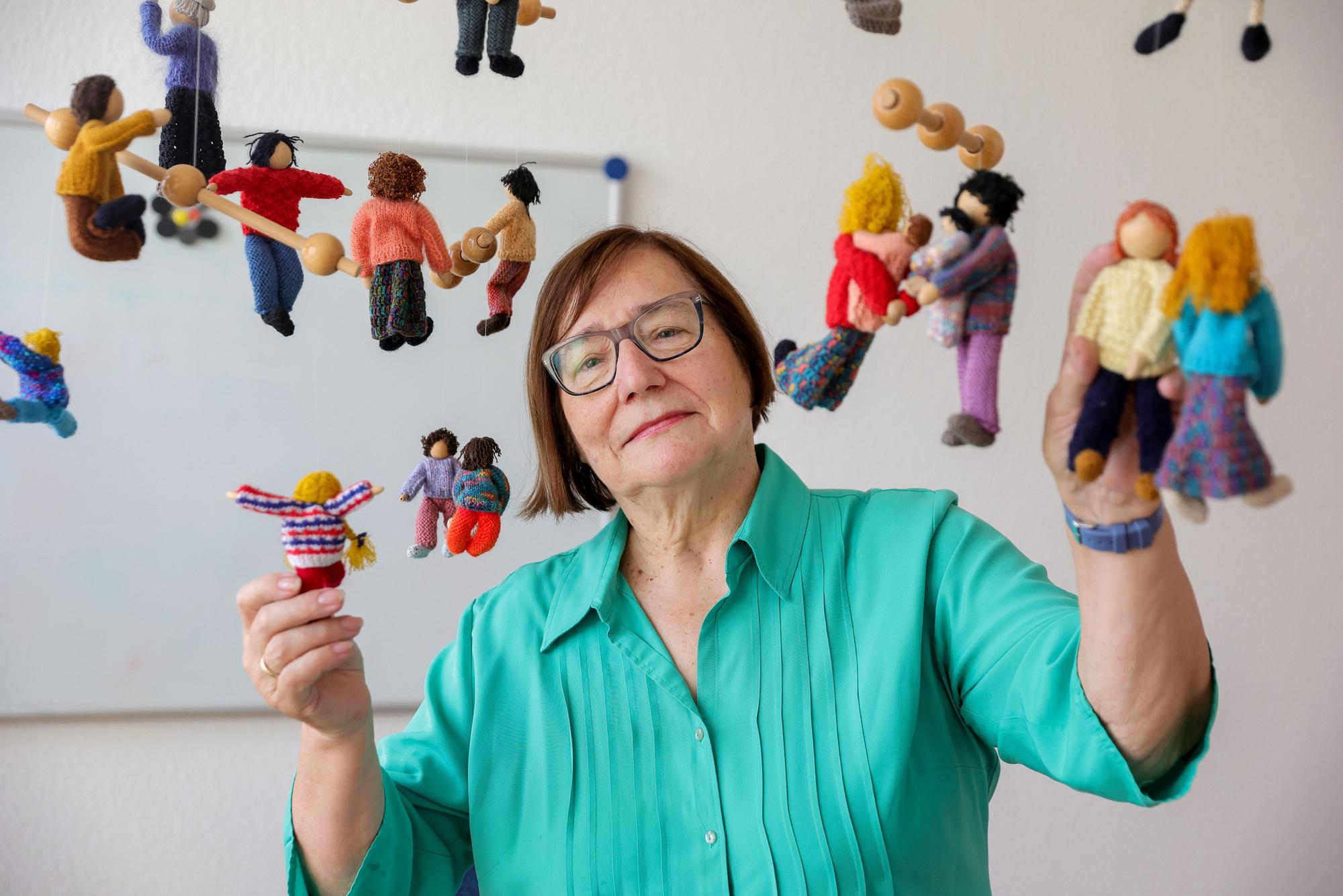 Die scheidende Vorsitzende des Kölner Kinderschutzbunds Marlis Herterich steht unter einem Mobile mit gestrickten Kindern.