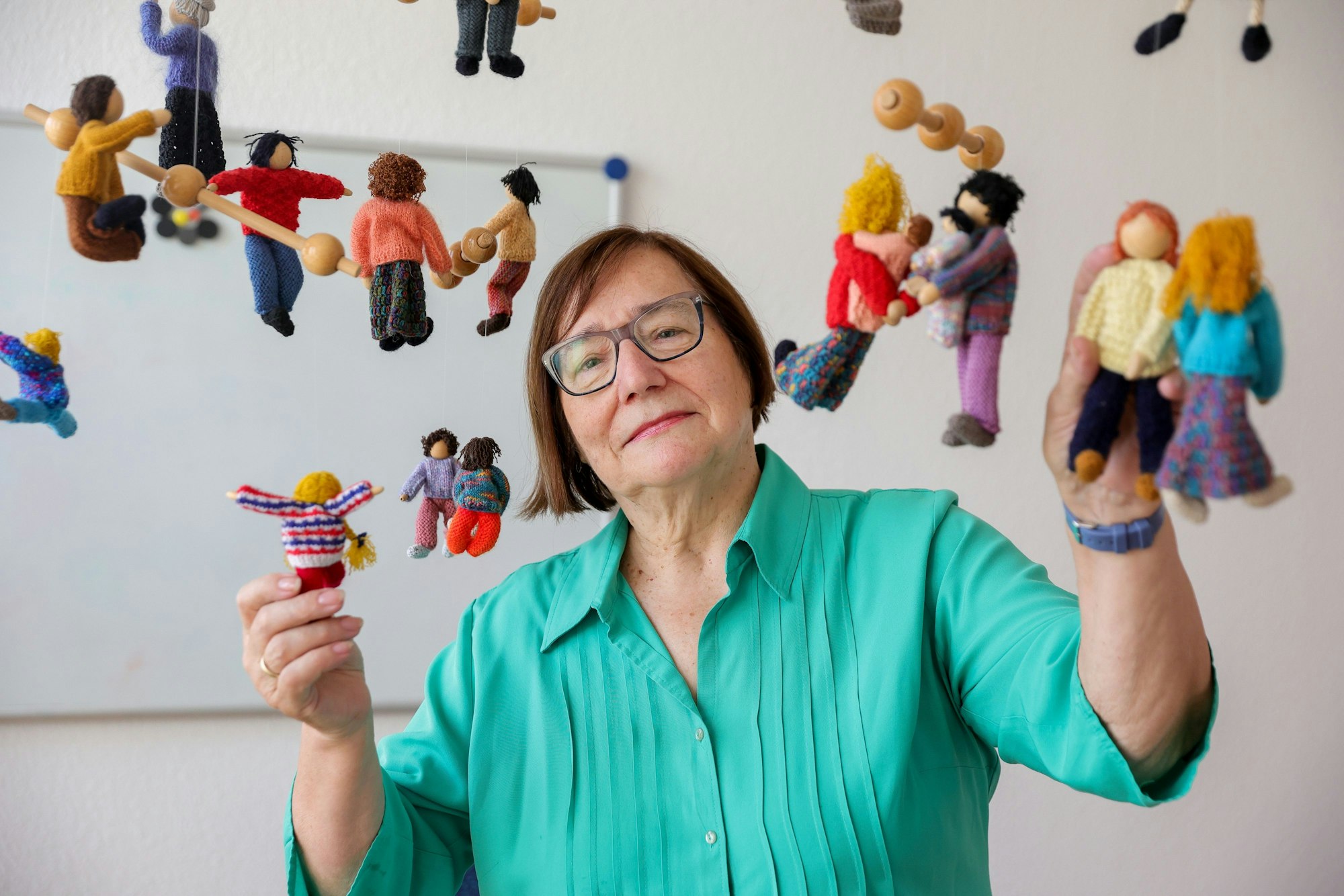 Die scheidende Vorsitzende des Kölner Kinderschutzbunds Marlis Herterich steht unter einem Mobile mit gestrickten Kindern.