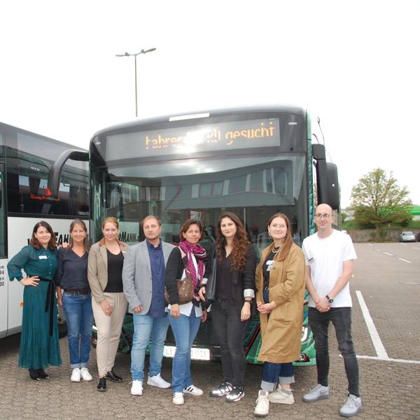Sechs Frauen und zwei Männer stehen vor Bussen.