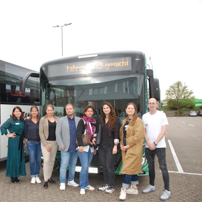 Sechs Frauen und zwei Männer stehen vor Bussen.