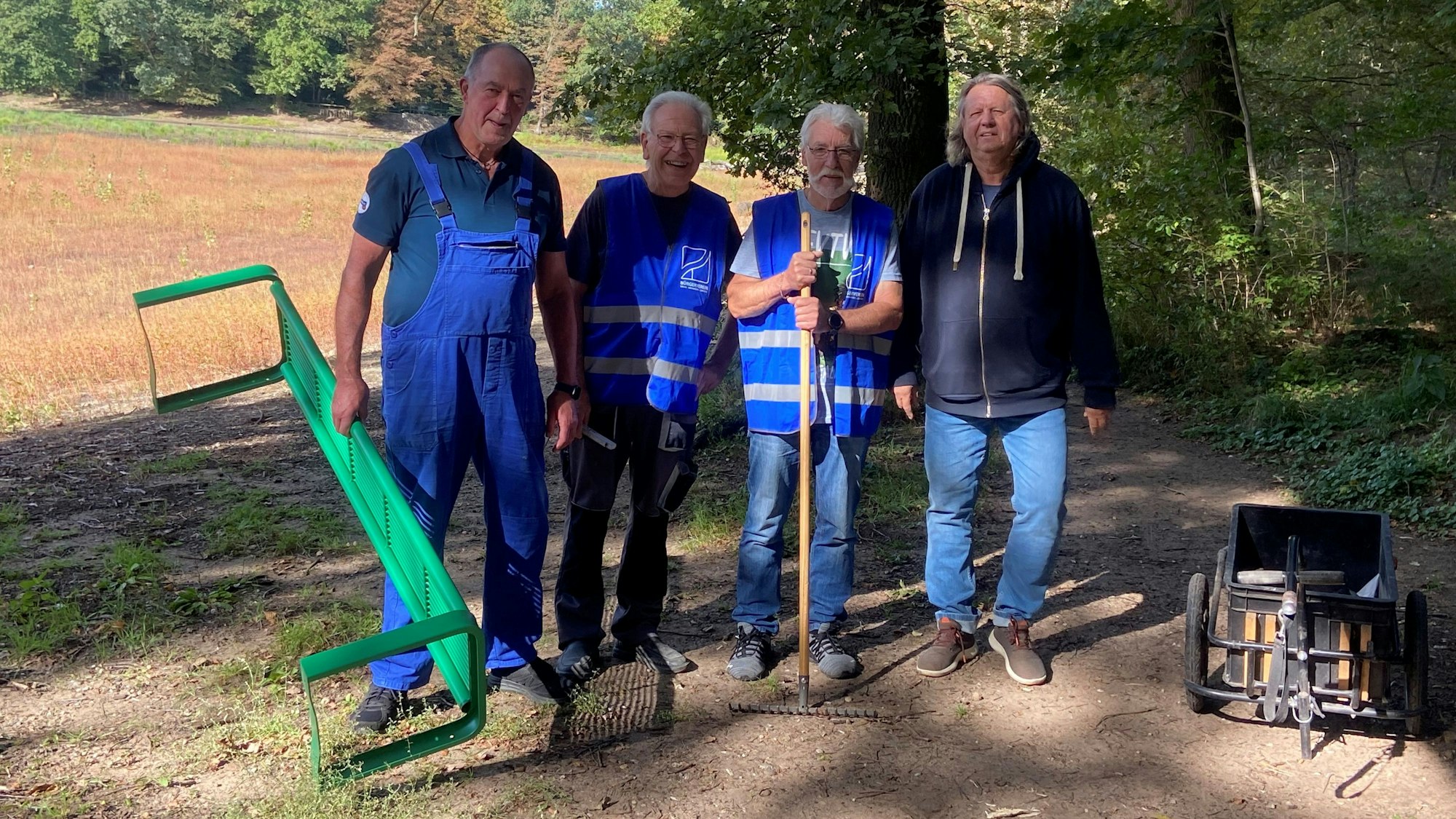 Ludwig Stutzbecher, Gerhard Möller, Willi Brandenburg und Roland Kulik (v.l.n.r.) installieren eine neue Bank am ausgetrockneten unteren Scheuerteich, der im Hintergrund zu sehen ist.