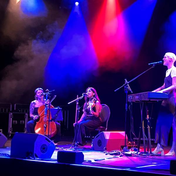 Drei Musikerinnen auf einer Bühne am Keyboard, Geige und Cello.