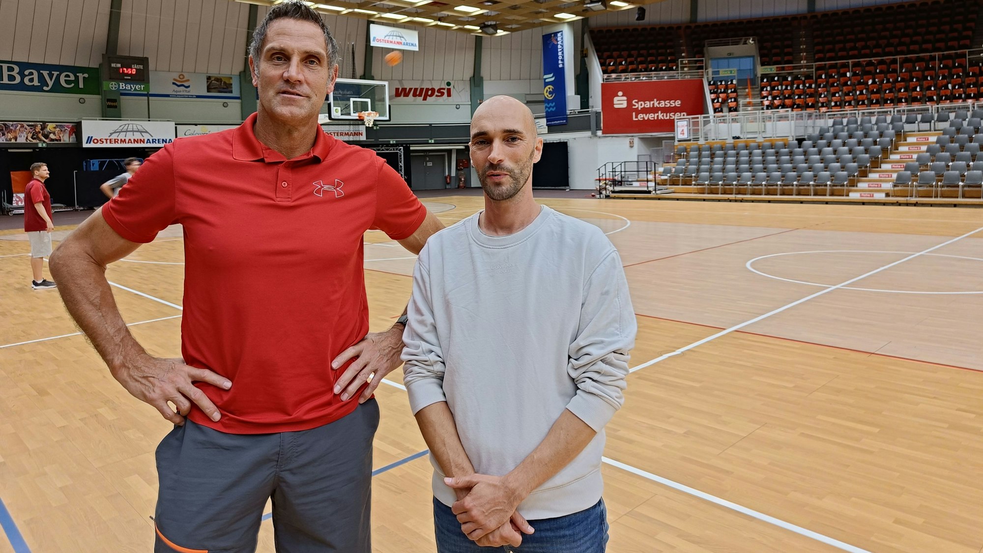 Zwei Männer stehen vor einem Basketball-Feld.
