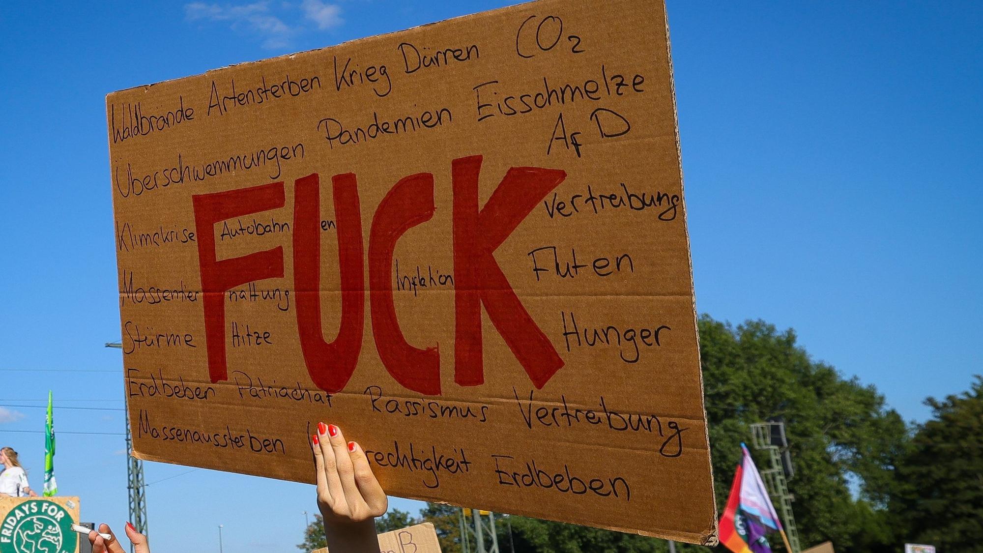 Eine junge Frau hält ein Pappschild mit der Aufschrift „Fuck“ bei einem Protestzug der Klimaschutzbewegung Fridays for Future durch die Innenstadt. (Symbolbild)