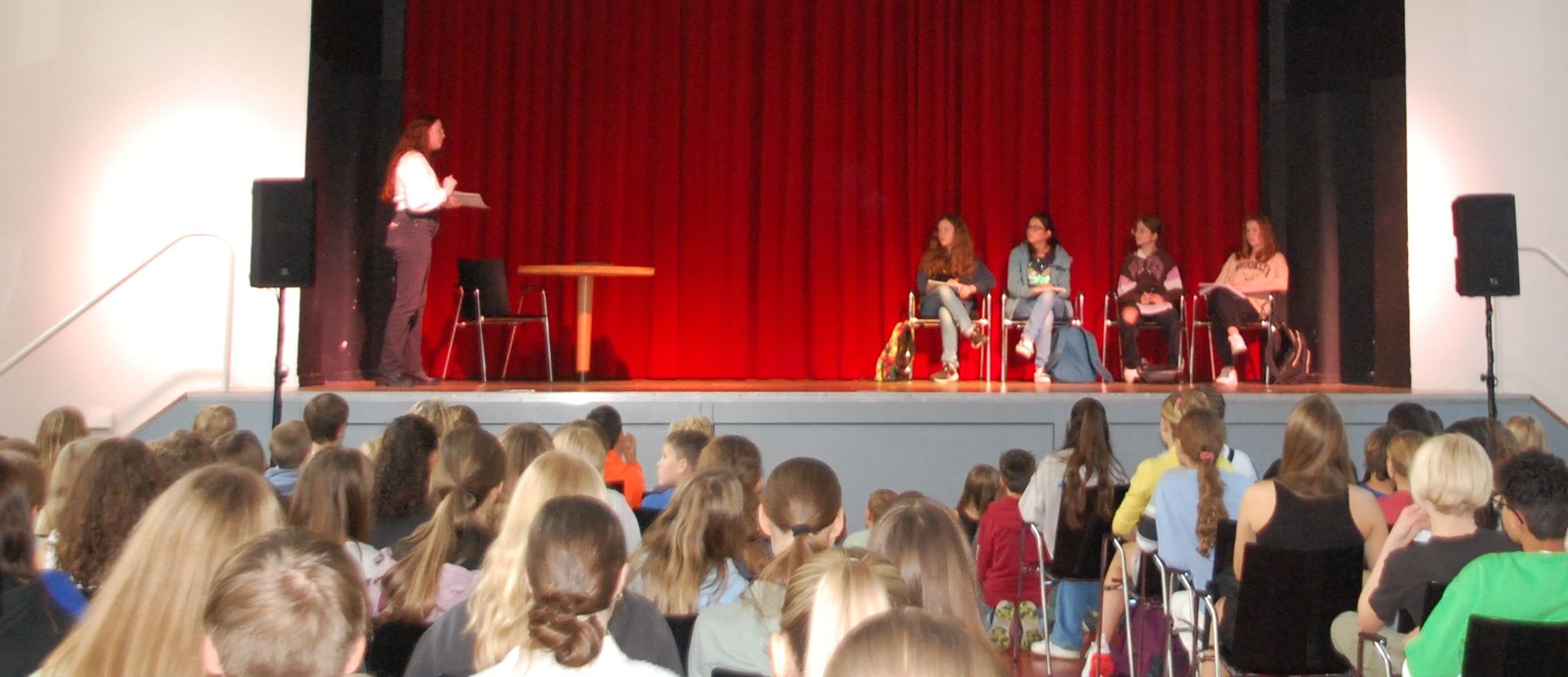 Eine Gruppe von Schülerinnen und Schülern präsentiert ihr szenisches Spiel über psychische Erkrankungen in der Aula der Marienschule.