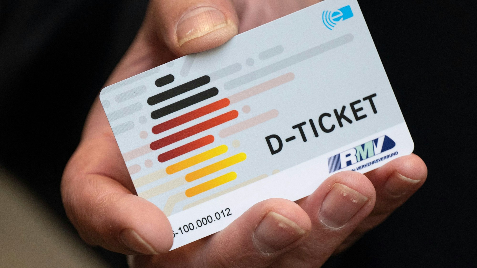 Eine Person hält ein Deutschland-Ticket in der Hand.
