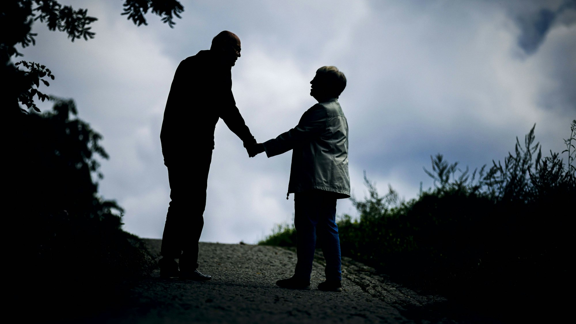 Symbolfoto: Ein altes Ehepaar läuft Hand in Hand bei einem Spaziergang gemeinsam einen Weg entlang.
