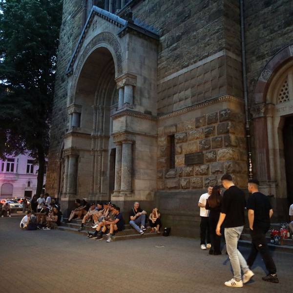 Menschen sitzen rund um die Kirche Sankt Michael am Brüsseler Platz.