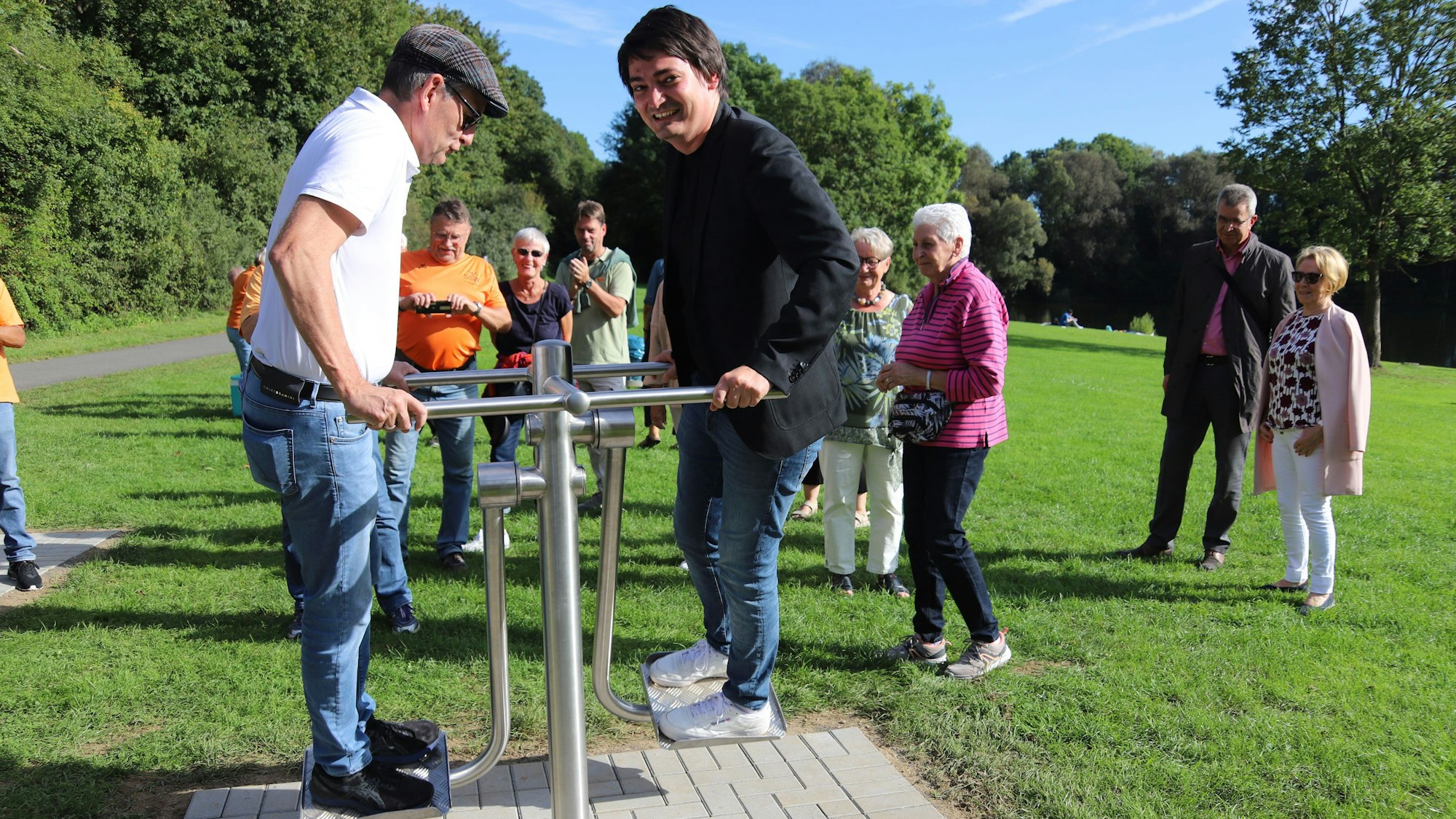 Der Stadtsportverband Hennef hat aus dem Programm Moderne Sportstätte II des Landes NRW an drei Standorten Outdoor-Sportgerät für rund 65000 Euro angeschafft. Am Allner See war Einweihung. Bürgermeister Mario Dahm, der ein schwarzes Sakko trug, (r.) und der Präsident des Stadtsportverbandes, Hajo Noppeney, im weißen T-Shirt testeten die Geräte.