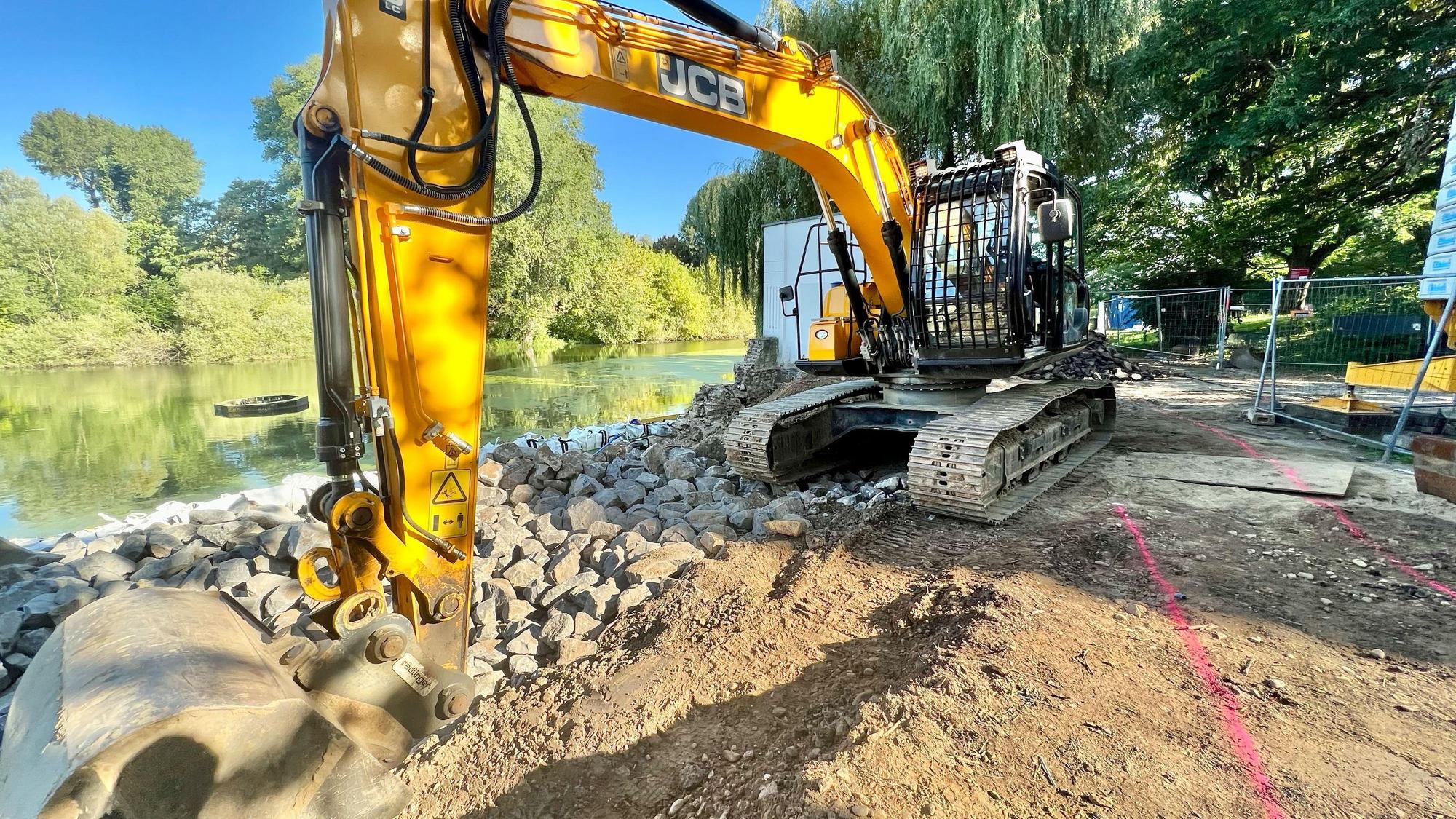 Die Ufermauer neben dem Teehaus an einem der Groov-Teiche in Zündorf wird saniert. Davor steht ein Bauer.