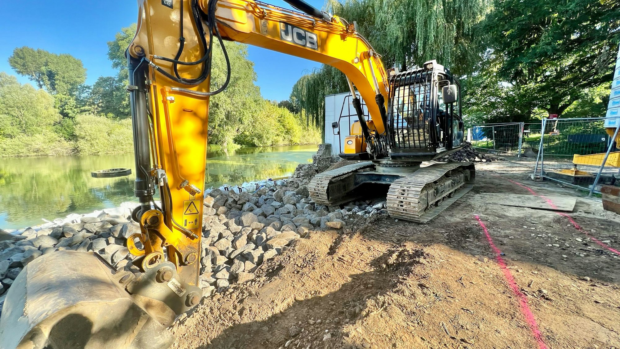 Die Ufermauer neben dem Teehaus an einem der Groov-Teiche in Zündorf wird saniert. Davor steht ein Bauer.
