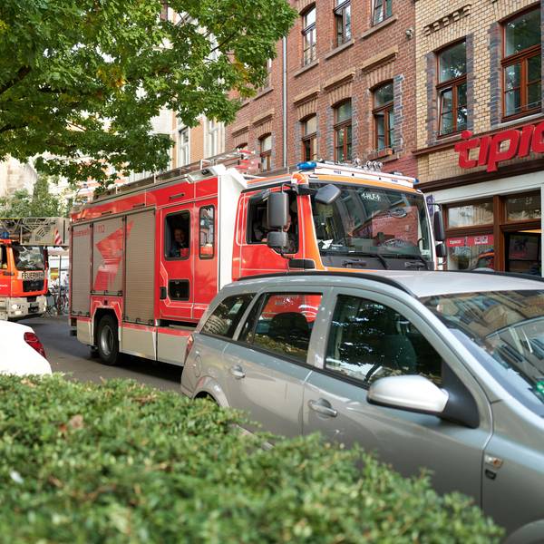 Zu sehen sind zwei Einsatzfahrzeuge der Kölner Feuerwehr, die an einem falsch parkenden Auto vorbeifahren wollen.