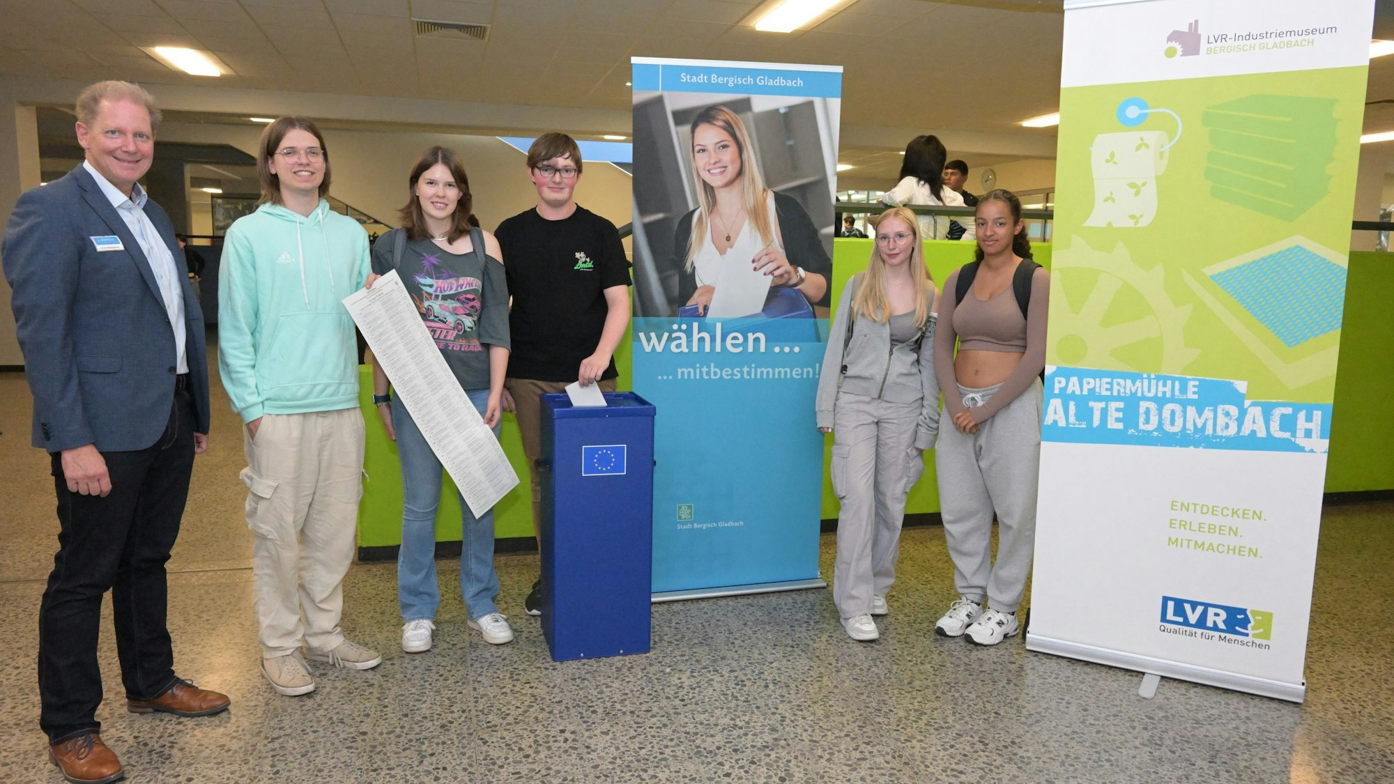 Neben einer Wahlurne stehen vier Schülerinnen und ein Schüler sowie Frank Bodengesser.