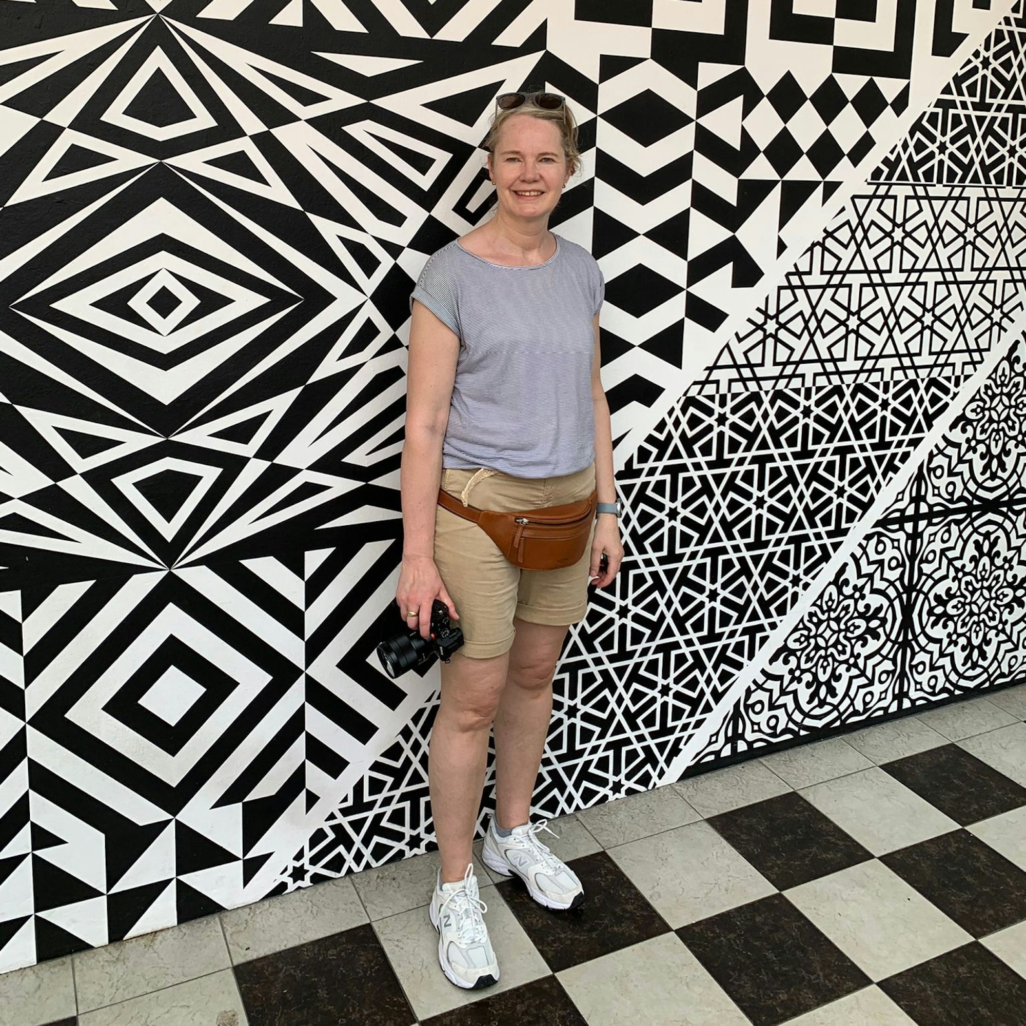 Kerstin von Berg steht vor einer gemusterten Wand.