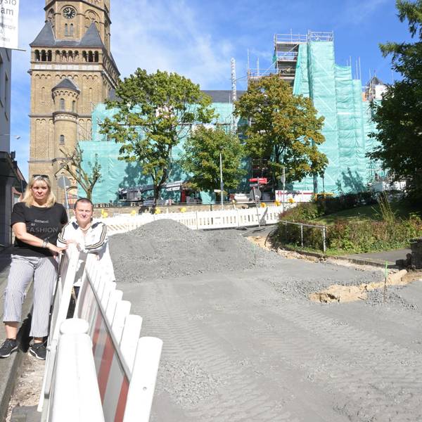 Susanne und Frank Kramm stehen vor einem Bauzaun.
