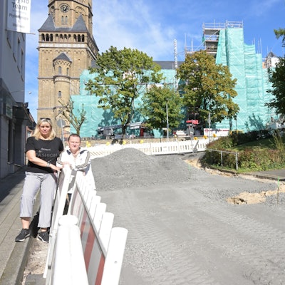 Susanne und Frank Kramm stehen vor einem Bauzaun.
