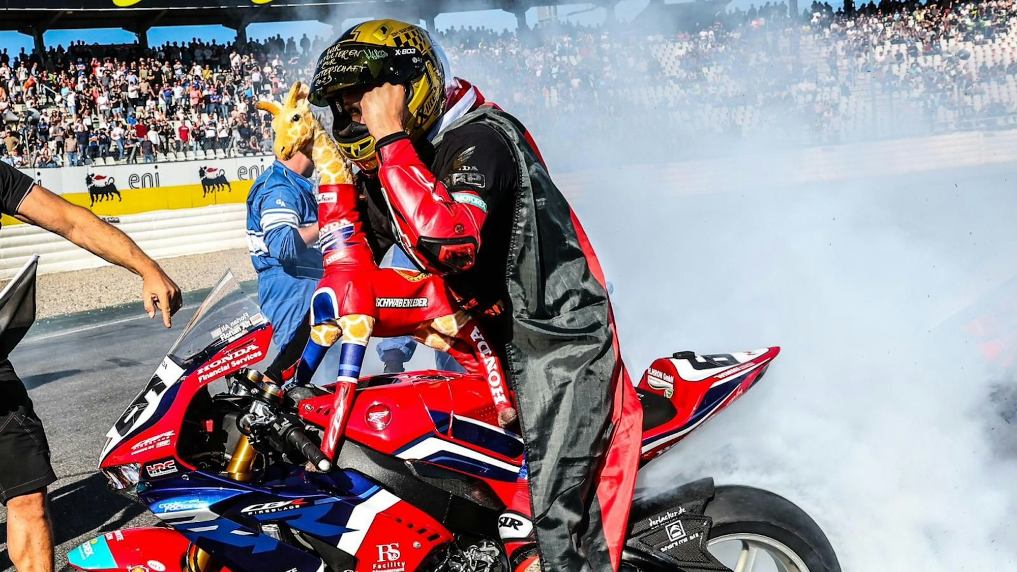 Florian Alt sitzt mit Deutschlandfahne um den Schultern auf einem Motorrad.