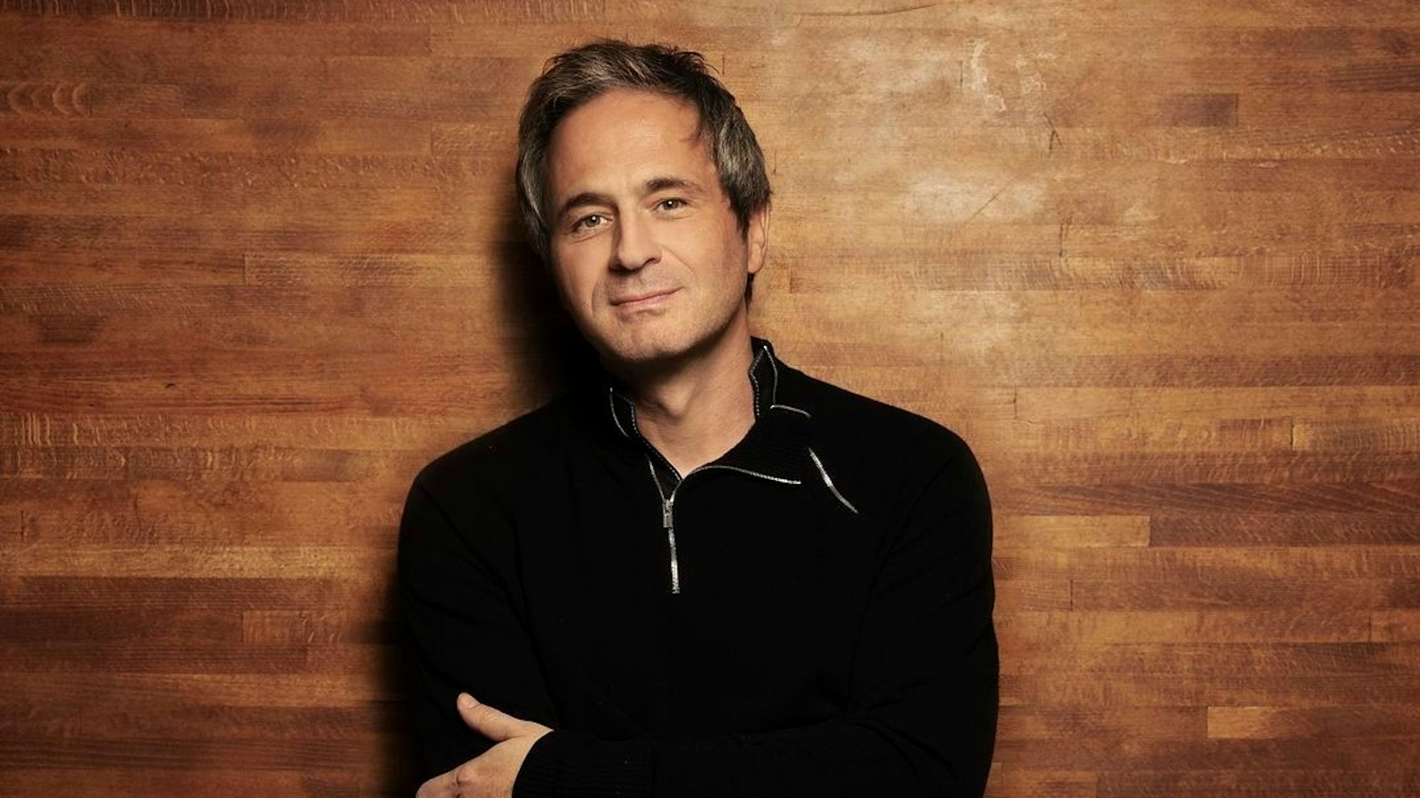 Piotr Anderszewski trägt einen schwarzen Pullover, im Hintergrund ist eine Holzwand.