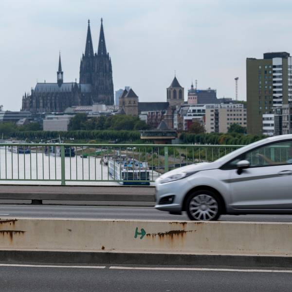 Ein Auto fährt über die Zoobrücke in Köln, im Hintergrund ist der Kölner Dom zu sehen.